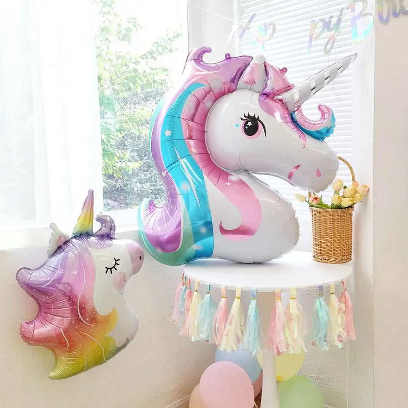 Unicorn head balloon floating above a birthday party table