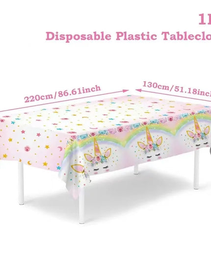 Rainbow unicorn tablecloth in white with pastel rainbow border and gold stars on a party table