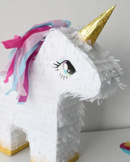 Unicorn pinata shown with blindfold and stick for party games